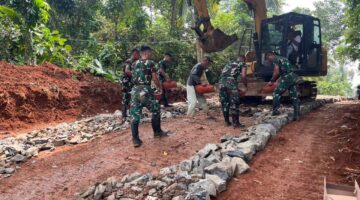 Satgas TMMD Ke-126 Kodim 0601/Pandeglang Lanjutkan Pengerasan Jalan dengan Bantuan Alat Berat Ekskavator, Batu Disebar untuk Dasar yang Kokoh